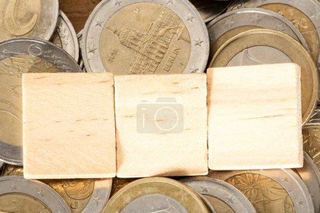 Photo for Wooden cubes on pile of euro coins - Royalty Free Image
