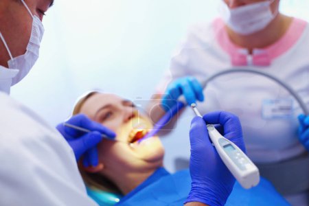 Téléchargez les photos : Portrait d'un dentiste qui soigne les dents d'une jeune patiente. - en image libre de droit