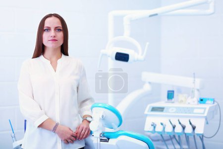 Téléchargez les photos : Femme dentiste debout dans son bureau souriant. - en image libre de droit