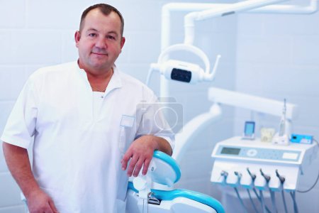 Foto de Retrato de un dentista sonriente de pie en la clínica dental. - Imagen libre de derechos