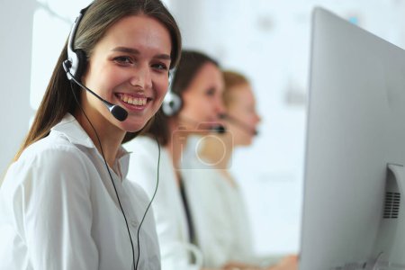 Lächelnde Geschäftsfrau oder Helpline-Betreiberin mit Headset und Computer im Büro.