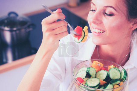 Téléchargez les photos : Jeune femme souriante préparant une salade dans la cuisine - en image libre de droit
