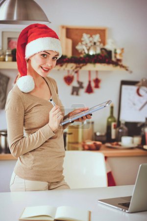 Photo for Smiling young woman in the kitchen, isolated on christmas background - Royalty Free Image