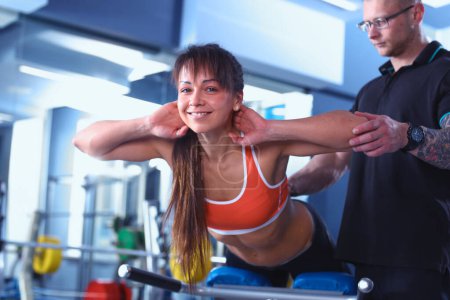Photo for Beautiful woman at the gym exercising with her trainer . Beautiful woman - Royalty Free Image