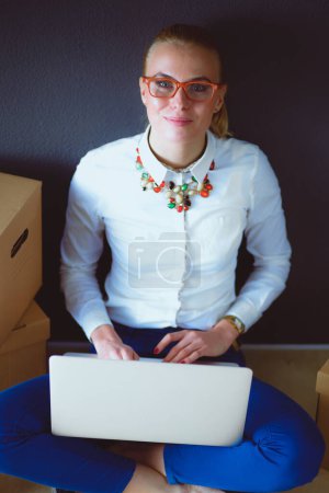 Photo for Woman sitting on the floor near a boxes with laptop . Businesswoman. - Royalty Free Image