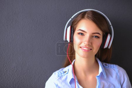 Téléchargez les photos : Jeune fille heureuse assise sur le sol et écoutant de la musique
. - en image libre de droit