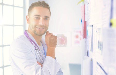 Téléchargez les photos : Jeune et confiant portrait de médecin masculin debout dans le bureau médical - en image libre de droit