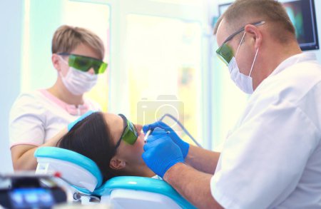 Téléchargez les photos : Portrait d'un dentiste qui soigne les dents d'une jeune patiente. - en image libre de droit