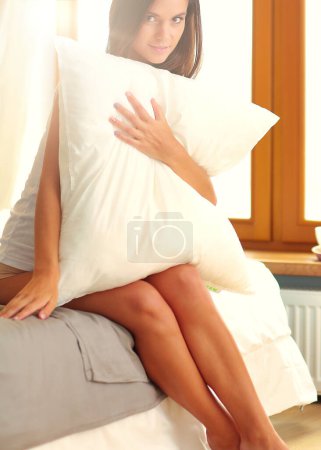 Téléchargez les photos : Jeune femme assise au lit avec une tasse de lait
. - en image libre de droit