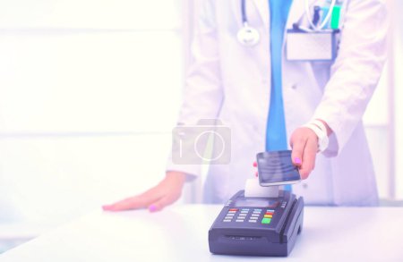 Foto de El doctor tiene la terminal de pagos en sus manos. Pagar por atención médica. Doctor.. - Imagen libre de derechos