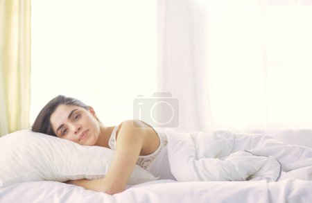 Photo for Pretty woman lying down on her bed at home. - Royalty Free Image