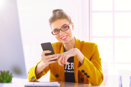 Téléchargez les photos : Femme d'affaires assise au bureau avec ordinateur portable au téléphone
. - en image libre de droit