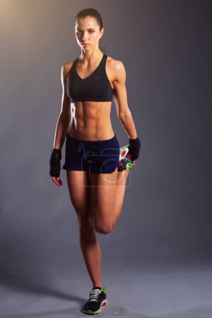 Téléchargez les photos : Musclé jeune femme posant en vêtements de sport sur fond noir - en image libre de droit