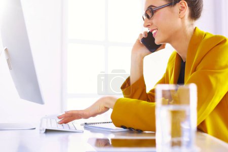 Téléchargez les photos : Femme d'affaires se concentrant sur le travail, en utilisant l'ordinateur et le téléphone portable dans le bureau. - en image libre de droit