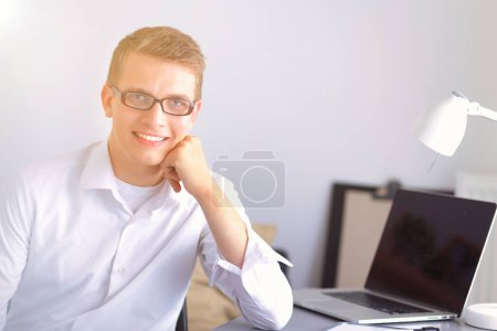 Photo for Young businessman working in office, sitting at desk - Royalty Free Image
