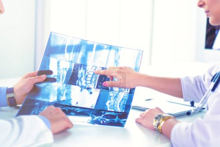 Photo for Two doctors studying x-ray image, consulting in bright office. - Royalty Free Image