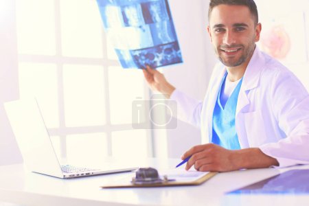 Foto de El guapo doctor está hablando con una paciente joven y tomando notas mientras está sentado en su consultorio. - Imagen libre de derechos
