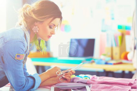 Photo for Fashion designer woman working with ipad on her designs in the studio. - Royalty Free Image