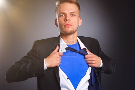 Photo for Young businessman acting like a super hero and tearing his shirt, isolated on gray background . - Royalty Free Image