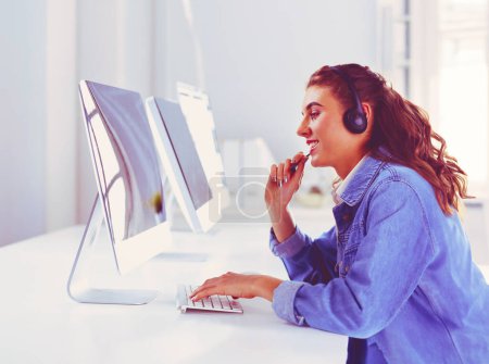 Téléchargez les photos : Femme d'affaires souriante avec casque à l'aide d'un ordinateur portable au bureau au travail
. - en image libre de droit