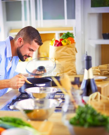Téléchargez les photos : Homme suivant la recette sur tablette numérique et la cuisine savoureuse et saine dans la cuisine à la maison. - en image libre de droit