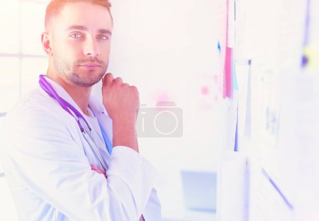 Téléchargez les photos : Jeune et confiant portrait de médecin masculin debout dans le bureau médical - en image libre de droit