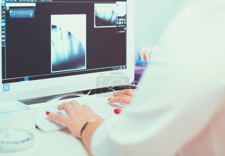 Photo for A female medical doctor looking at x-rays and using laptop in a hospital. - Royalty Free Image
