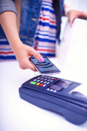 Téléchargez les photos : Client paie avec smartphone dans la boutique en utilisant la technologie NFC. Technologie NFC. Le client paie
. - en image libre de droit