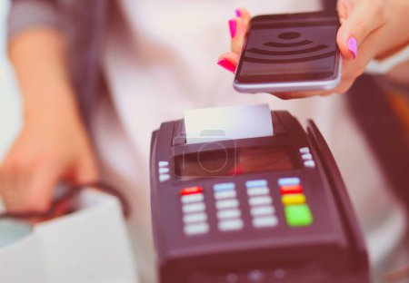 Foto de El cliente está pagando con el teléfono inteligente en la tienda utilizando la tecnología NFC. Tecnología NFC. Cliente está pagando
. - Imagen libre de derechos