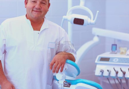 Téléchargez les photos : Portrait d'un dentiste souriant debout dans une clinique dentaire. - en image libre de droit