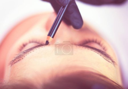Téléchargez les photos : Cosmetologue Appliquer un maquillage permanent sur les sourcils. - en image libre de droit
