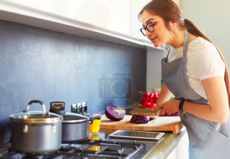 Foto de Mujer joven usando una tableta para cocinar en su cocina. - Imagen libre de derechos