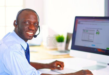 Foto de Hombre de negocios afroamericano con auriculares trabajando en su computadora portátil. - Imagen libre de derechos