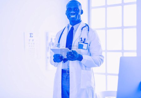 Photo for Male black doctor worker with tablet computer standing in hospital. - Royalty Free Image