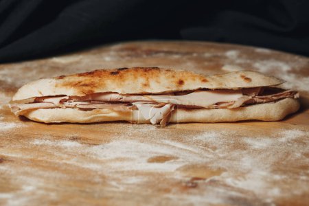 Un délicieux sandwich à la dinde repose sur une planche à découper rustique en bois, présentant des ingrédients frais et un savoir-faire culinaire.