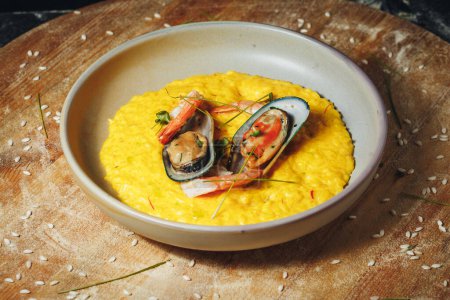A vibrant bowl filled with golden risotto, topped with succulent shrimp and plump mussels, showcasing a delectable seafood dish.