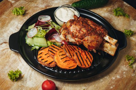 Ein schön arrangierter Teller mit Fleisch und Gemüse ruht auf einem Holztisch und präsentiert eine köstliche und gesunde Mahlzeit..