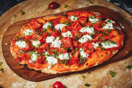 A delicious pizza topped with fresh tomatoes and melted cheese rests on a rustic wooden board.