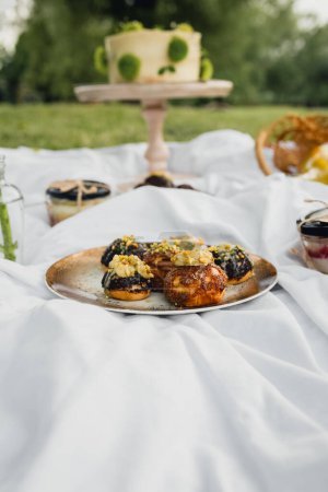 A picnic table set with a spread of delicious food and desserts, inviting a gathering in a serene outdoor setting.
