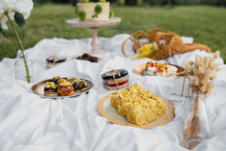 A picnic table adorned with a variety of food and drinks, inviting a scene of leisurely dining and enjoyment outdoors on a sunny day.