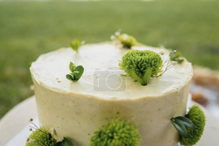 Un pastel blanco bellamente decorado con intrincadas flores verdes en la parte superior, creando un centro de mesa impresionante y elegante.