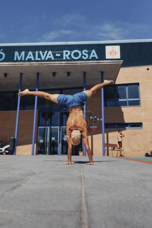 Photo for A talented man performs a perfect handstand in front of a majestic building, showcasing strength and balance. - Royalty Free Image