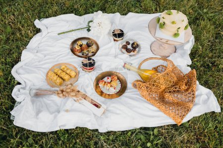 Eine lebendige Picknickdecke mit einer Auswahl an leckeren Speisen und erfrischenden Getränken für eine entspannende Mahlzeit im Freien.