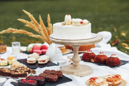 An array of delectable cakes and desserts beautifully displayed on a table set in a lush green park, inviting a delightful outdoor dining experience.