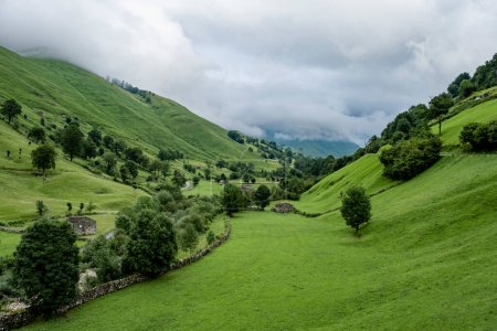 Foto de Prados y cabañas de piedra rústica en hermoso valle verde, Valles Pasiegos, Cantabria, España - Imagen libre de derechos