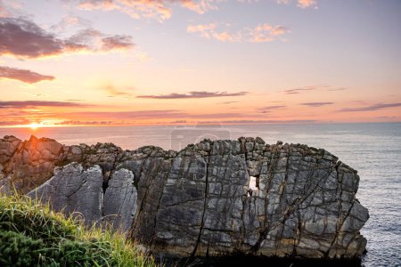 Foto de Acantilado empinado con hueco como una ventana tallado por la erosión. Hermoso paisaje costero al atardecer en la costa rota de Liencres, Cantabria, España - Imagen libre de derechos