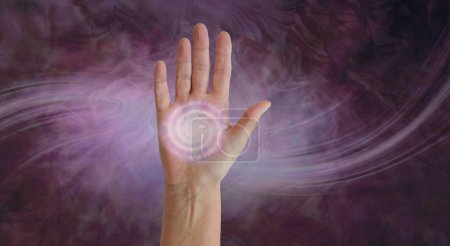 Photo for Diagram of palm chakra spinning energy vortex - open upright female hand with a pale pink spiral filling palm area against a flowing wispy deep red and light pink background with space for copy - Royalty Free Image
