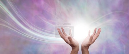 Photo for Sending beautiful healing intention across the ether - female open cupped hands with a white orb and trail of light against pastel pink and pale lime background with copy space - Royalty Free Image