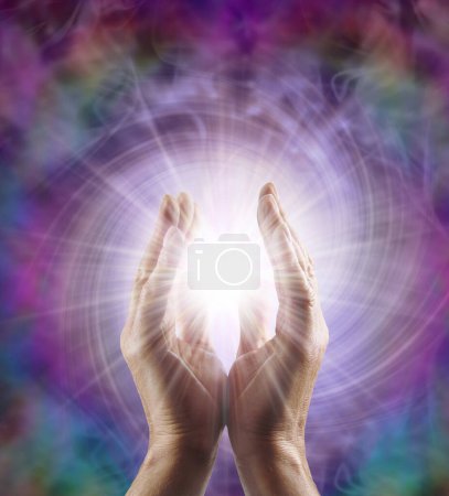 Reiki Master Healer sensing awesome vortexing energy field - male cupped hands reaching into a spiralling pink energy field with bright star orb between and copy space for message