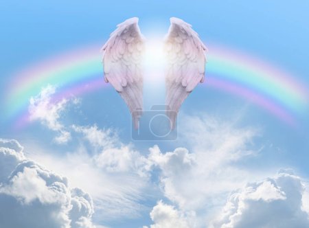 Foto de Angel Wings Rainbow Blue Sky Background - par de alas de ángel frente a un arco iris contra un hermoso cielo azul con nubes esponjosas ideales para un tema de bendición espiritual o religiosa - Imagen libre de derechos